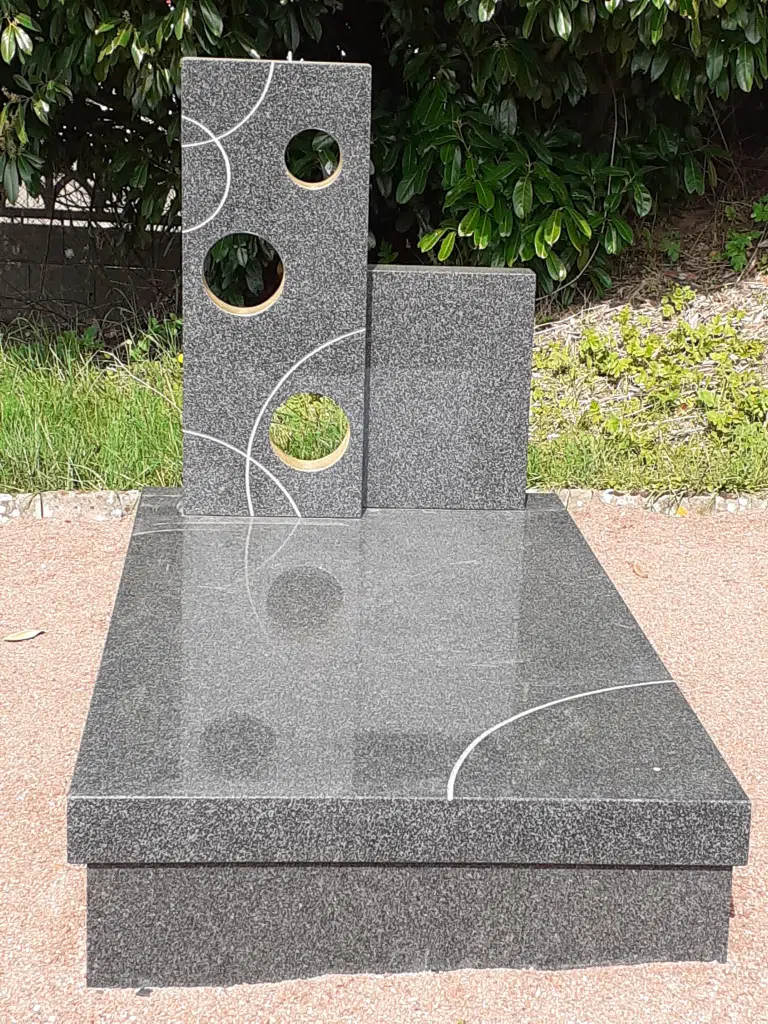 Pierre tombale moderne en granit sombre ornée de motifs géométriques.