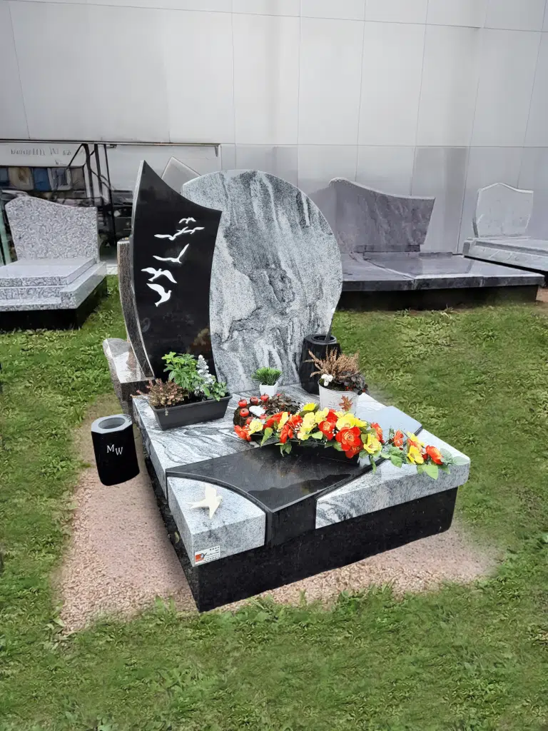 Monument cinéraire moderne avec stèle gravée d'oiseaux et fleurs colorées.